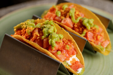 Mexican tacos with raw salmon, onion, and avocado guacamole on the blue dish fore restaurant menu 