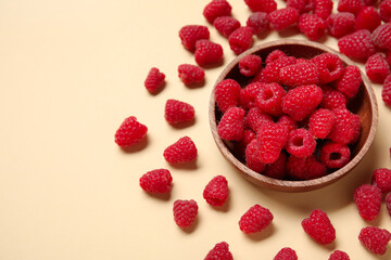 Bowl with fresh raspberries on yellow background