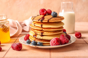 Plate of tasty pancakes with raspberries and blueberries on table
