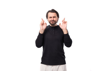 handsome brutal european macho man with black hair and beard with an earring in his ear crossed his...