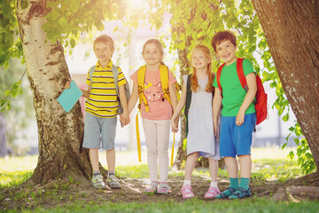 Fototapeta premium Group of children standing with backpacks near the school.