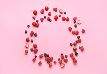 Frame made of fresh raspberries, blueberries and strawberries on pink background