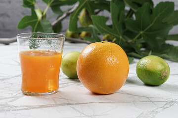 Succo d'arancia nel bicchiere con ghiaccio e arancia sul tavolo