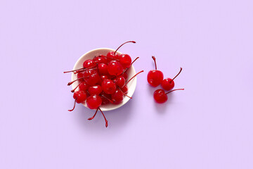 Bowl of tasty maraschino cherries on lilac background