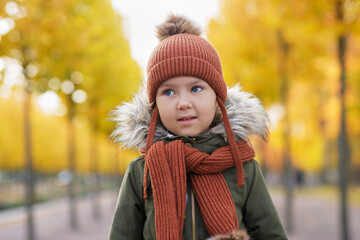 portrait of little girl walking in autumn city park