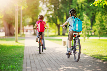Two boys with backpacks on bicycles going to school. - 620144295