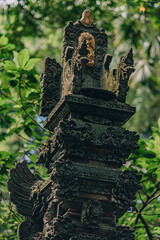 Close up shot of temple sculpture in sacred monkey forest on green nature background. Stone curved balinese architecture
