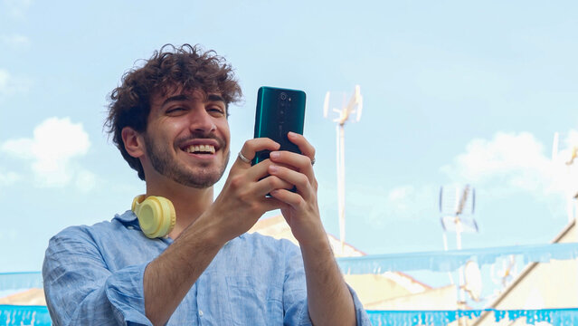 Happy young man ichatting with smartphone in a seaside town during vacation