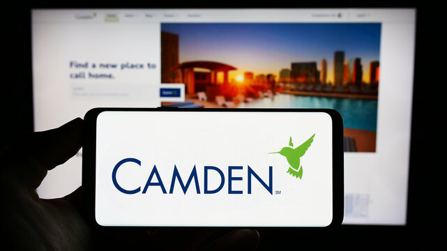 Stuttgart, Germany - 06-25-2023: Person holding cellphone with logo of US real estate company Camden Property Trust on screen in front of business webpage. Focus on phone display.