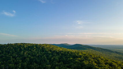 Aerial view of the Peak of the mountain range and tall forest near to the river at summer cloud evening with horizon, low height, blue