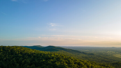 Naklejka premium Aerial view of the Peak of the mountain range and tall forest near to the river at summer cloud evening with horizon, color, sky