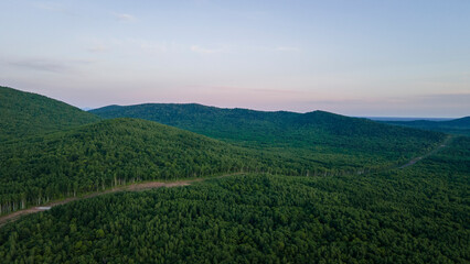 Aerial view of the Mountain range and tall forest near to the river at summer cloud evening with incredible horizon, blue color