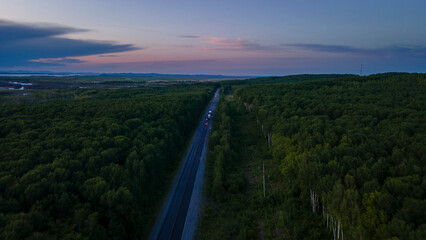 Aerial view of the Slope of a Mountain Range and tall taiga near to the river at summer cloud evening with purple horizon