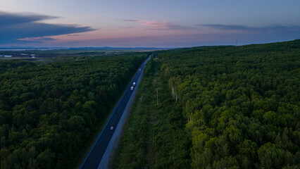 Aerial view of the Slope of a Mountain Range and tall taiga near to the river at summer cloud evening with horizon, purple color