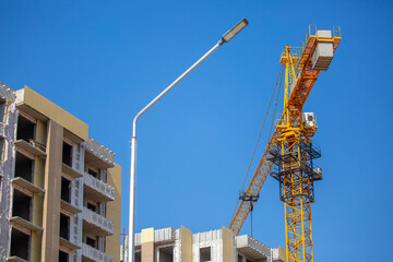 Load-lifting crane on a construction site against the blue sky. A group of lifting platforms for construction and handling operations. Close-up of a basket for transporting people