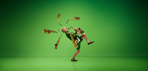 Creative design. Artistic, expressive man emotionally playing saxophone against green studio...