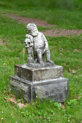 
19th Century statue representing a young baby leaning on a human skull in cemetery