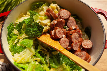 Cooked cabbage kale and sausage stew in red pod top view
