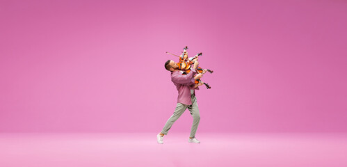 Creative collage. Talented, emotional young man playing violin against pink studio background. Concept of music, talent, hobby, entertainment, festival, performance, ad © master1305