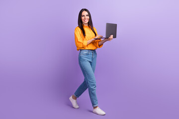 Full size photo of pleasant satisfied woman dressed oversize shirt hold laptop go to empty space isolated on violet color background