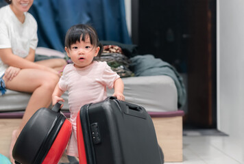Fototapeta na wymiar Asian baby girl holding suitcases prepare for vacation travel, Happy family activity concept.
