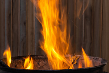 Black metal round barbeque with fire for a picnic is in the terrace