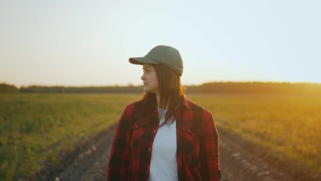 A farmer girl in a cap walks through agricultural land, looks around.