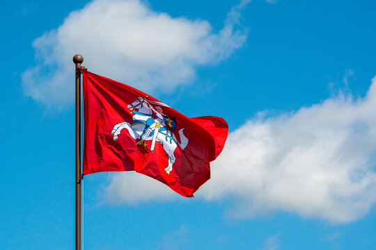 Historical Lithuanian flag waving in the wind against blue sky