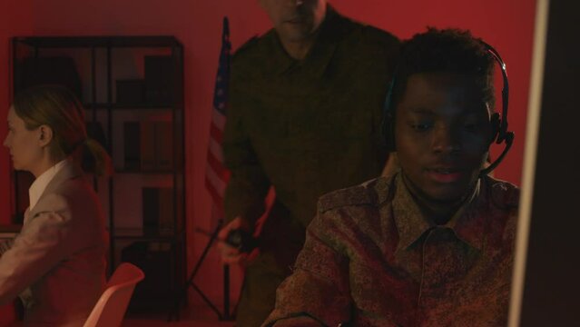 Medium full shot of three multiracial military officers having emergency situation in surveillance hub at night