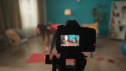 A female trainer uses a camera to record new content for an online fitness. A woman filming a video...