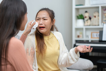 Two women talking about problems at home. Asian women embrace to calm their sad best friends from feeling down. Female friends supporting each other. Problems, friendship, and care concept