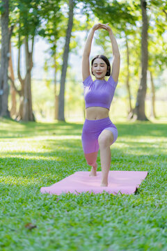 Healthy Thai Asian woman doing yoga in the evening at the park. Health and outdoor activities concept with plants as background on green grass. vertical image
