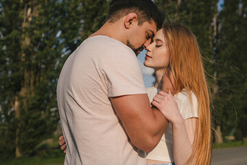 Fototapeta premium Couple lovers hugging and kissing in the park at sunset. Love, youth, happiness concept.