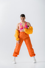 fashion trend, warm clothing, fashionable young woman with short hair posing in puffer jacket and...