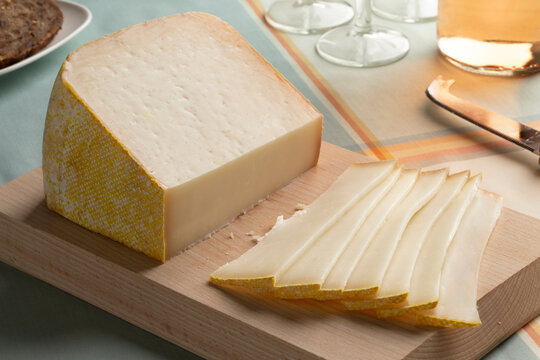 Piece of Chistera chevre and brebis, sheep and goat cheese and slices on a cutting board close up 