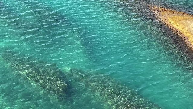 Blue clear flowing sea water and coastal rock.