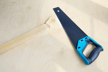 sharp hacksaw on wooden surface with sawed-off piece of board next to it