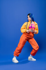 full length, dyed hair, fashion forward, tattooed female model with blue hair posing in puffer...
