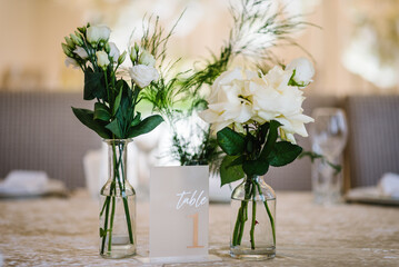 Table number 1. Stands, sign number one. Setup detail. Luxury reception. Elegant table decorated composition flowers in party area. Beautifully organized event. Wedding hall with atmospheric decor