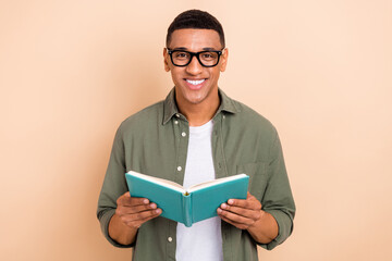 Photo of positive charming man wear khaki shirt eyeglasses reading interesting book isolated beige color background