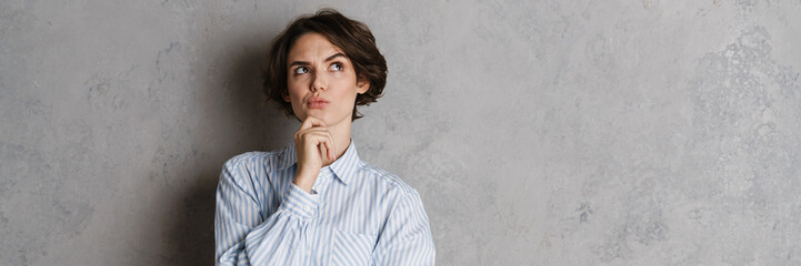Young brunette woman holding her chin and looking upward