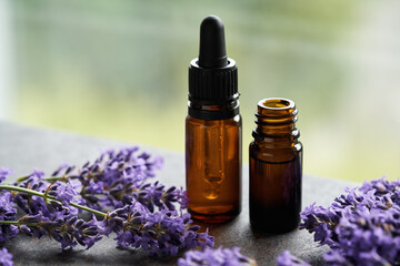 Fototapeta na wymiar Bottles of essential oil with blooming lavender plant
