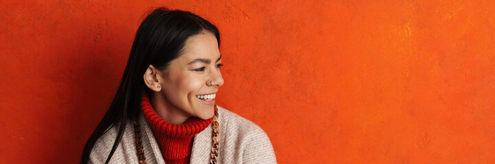 Young hispanic woman in coat smiling and looking aside