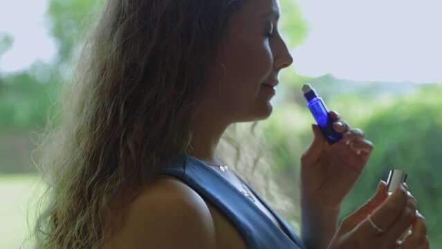 An attractive perfumer girl sniffs a jar of aroma oil and chooses a fragrance for herself.against the backdrop of nature and greenery. The concept of creating your own natural fragrance