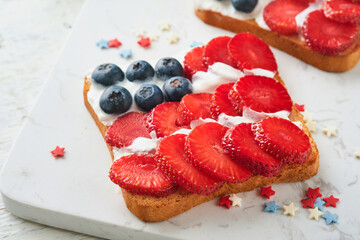 4th of July American Independence Day food. American flag sandwich with strawberries, blueberries, whipped sweet cream, soft cheese on toast bread. Independence or Patriotic Day breakfast idea Mock up