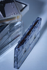 Audio cassette resting on a white surface, near a pile of cassettes.