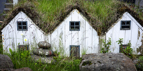 Fototapeta na wymiar Three small white wooden elf houses with grass roof, typical for Iceland. 