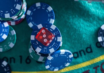 Red dice, game cards and colored chips for playing poker on gaming table in casino. Concept of gambling, betting, leisure. Background of poker game, entertainment, risk, gaming lifestyle. Close up.