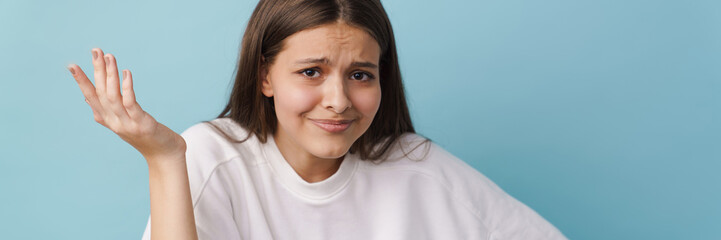 Young white brunette woman frowning and holding copyspace