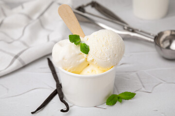 Delicious ice cream with mint and vanilla pods on white textured table, closeup
